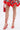 A person in a floral dress with a red hem pairs it with the AKIRA JANIKA RED HARDWARE STRAPPY SANDAL and a matching red handbag. The photo, focused on their legs and feet, highlights the chic strappy sandal.