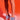 Against a red background, a person shows off their legs from mid-thigh down while wearing the AZALEA WANG JANSEN BLUE SNAKE STILETTO SANDAL with a chic snakeskin pattern and holding a sparkly handbag.