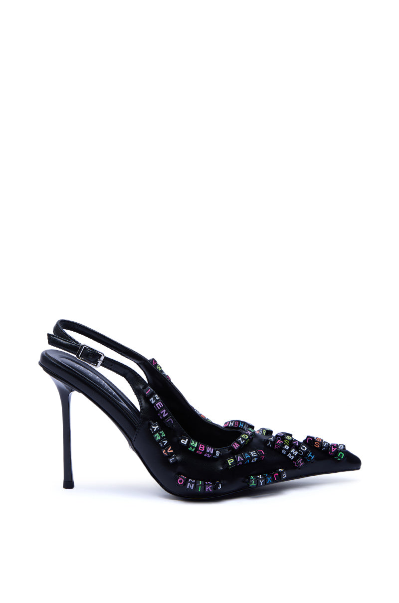 The AKIRA LETTER BEAD EMBELLISHED SLING BACK NOVELTY PUMP is a black faux leather stiletto with a pointed toe, colorful beaded lettering on the straps and upper, styled against a plain white background.