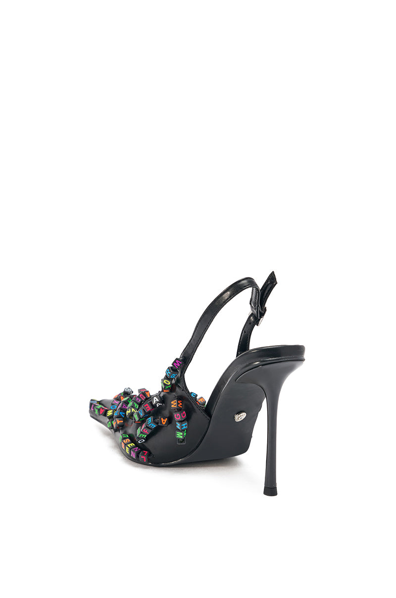 The AKIRA LETTER BEAD EMBELLISHED SLING BACK NOVELTY PUMP is a black faux leather stiletto sandal with a slingback strap and colorful letter bead accents, displayed at an angle on a plain white background. 9