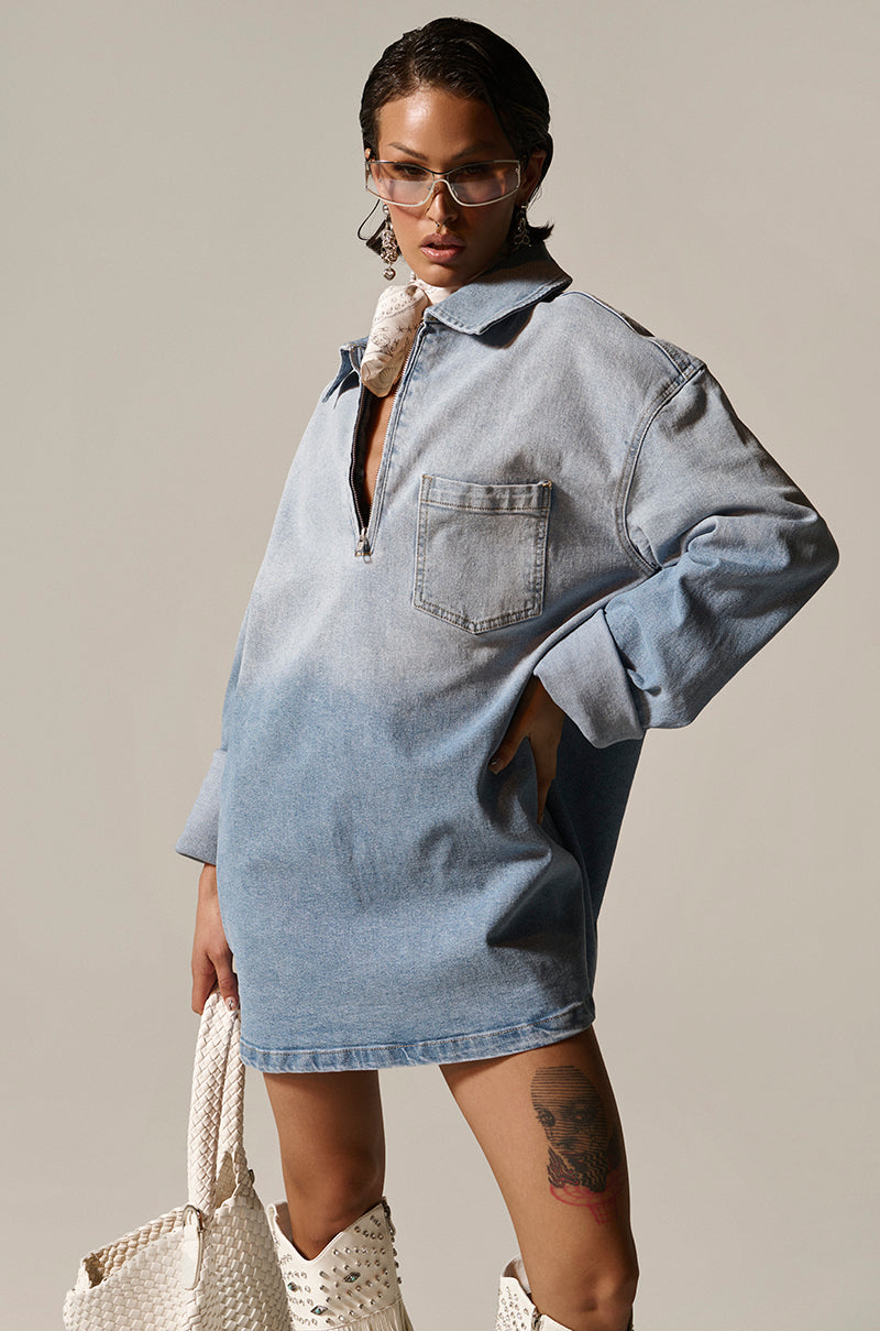 Wearing the COOL GIRL OVERSIZED OMBRE DENIM SHIRT DRESS, they showcase bold style with a zip-up collar, large front pocket, sunglasses, a chic neck scarf, a leg tattoo, and a woven white bag for a casual-cute look.