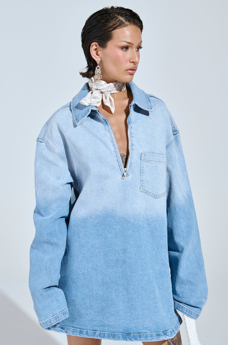 Wearing a COOL GIRL Oversized Ombre Denim Shirt Dress with a front pocket and zipper, large white lace choker, and statement earrings, they have slicked-back short hair and gaze to the side against a light backdrop, embodying the casual-cute style.