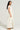 A woman with long, wavy hair stands in the YA YOU THOUGHT FRENCH TERRY JUMPSUIT, a light-colored, off-the-shoulder outfit crafted from a stretchy cotton blend. She faces forward while gazing to the side, paired with brown shoes against a neutral backdrop.