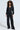 A person with curly hair confidently wears the DOING THE MOST French Terry jumpsuit featuring a metallic front zip closure, rhinestone embellishments, large sunglasses, and black shoes against a plain light gray background.