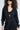 With curly hair and large sunglasses, a person rocks the DOING THE MOST FRENCH TERRY JUMPSUIT WITH RHINESTONES over a black top, set against a plain light background, highlighting their stylish presence.