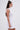 A woman with long straight brown hair, styled half-up, wears the IDK FELT CUTE RIBBED KNIT MINI DRESS and large silver hoop earrings. She is standing in profile against a plain white background.