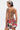 A woman with short, two-toned hair and tattoos poses in the STREETS ARE CALLING PRINTED RUFFLE ROMPER with an open lace-up back, looking over her shoulder against a plain white background.
