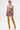 A woman with tattoos and short dark hair wears the STREETS ARE CALLING PRINTED RUFFLE ROMPER and tall mustard-yellow lace-up boots, styled in streetwear fashion against a plain white background.