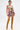 A woman with tattoos and slicked-back hair stands against a white background wearing the STREETS ARE CALLING PRINTED RUFFLE ROMPER, styled with vibrant knee-high boots for a bold streetwear look.