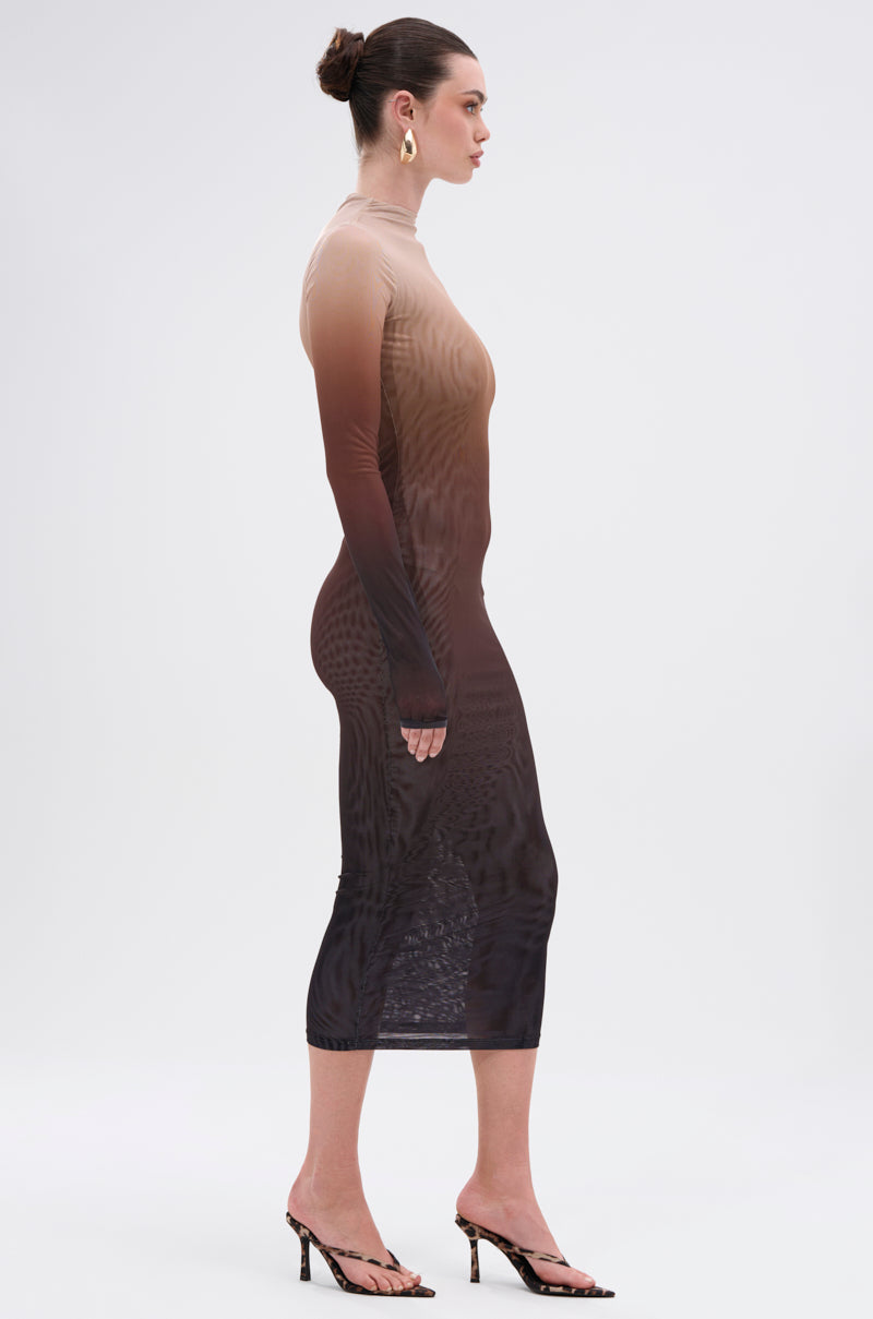 A woman in profile wears the FIFTY SHADES OMBRE MIDI DRESS, styled with heeled sandals, bold gold hoop earrings, and a neat bun, set against a plain light background.