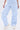 A person models the SUCKER FOR YOU SEERSUCKER JUMPSUIT in light blue and white stripes with a wide leg silhouette, standing against a white background. Only the lower body and one hand are visible, paired with white sneakers.