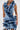 A woman wears the SAY IT AGAIN RUFFLED DENIM MINI DRESS, featuring bold vertical and diagonal ruffles across the front for a textured, statement-making look.