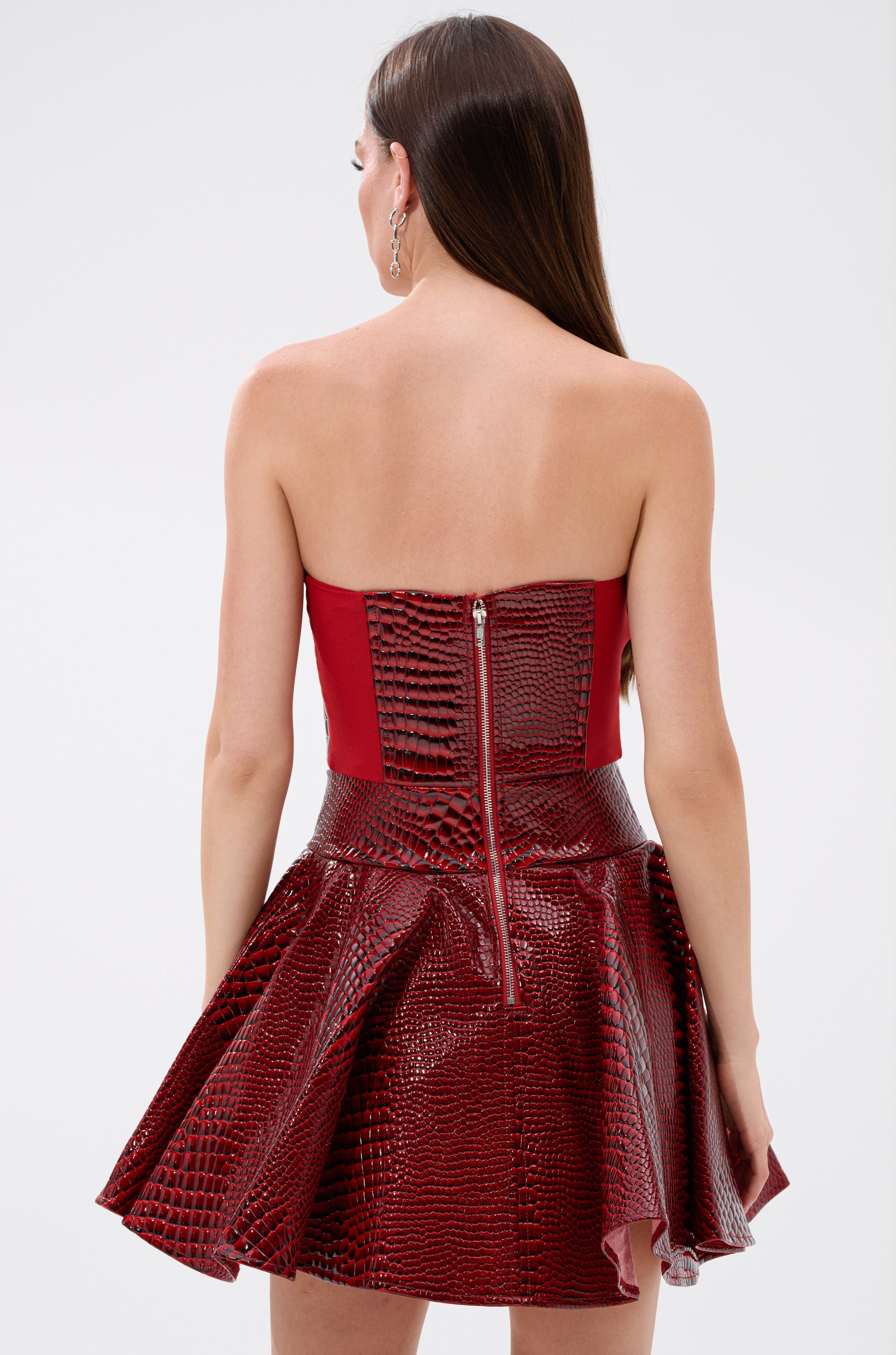 A woman in the VAL PU Mini Dress in croc print with a striking red corset bodice design.
