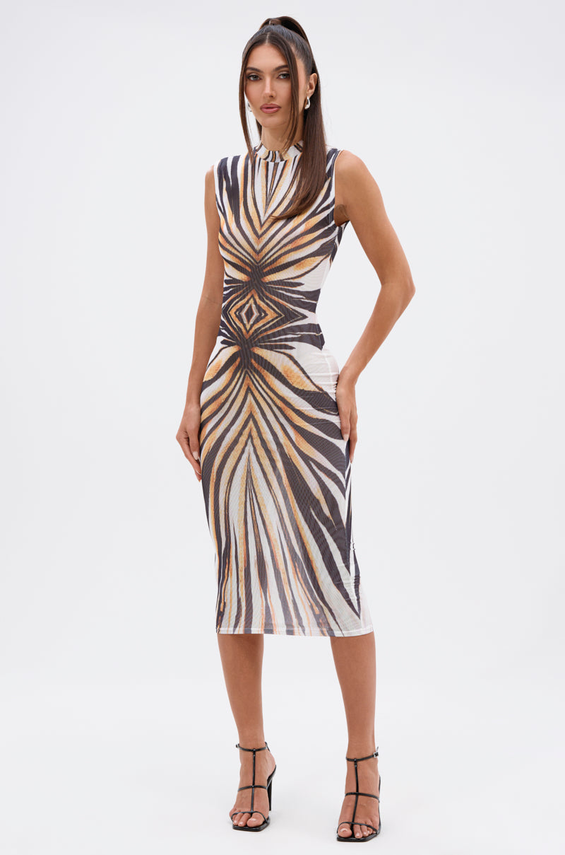 A woman stands against a plain white background wearing THE BOY'S ALL MINE PRINTED MIDI DRESS, a sleeveless bodycon midi featuring bold black, white, and gold geometric patterns, paired with black strappy heels. 0