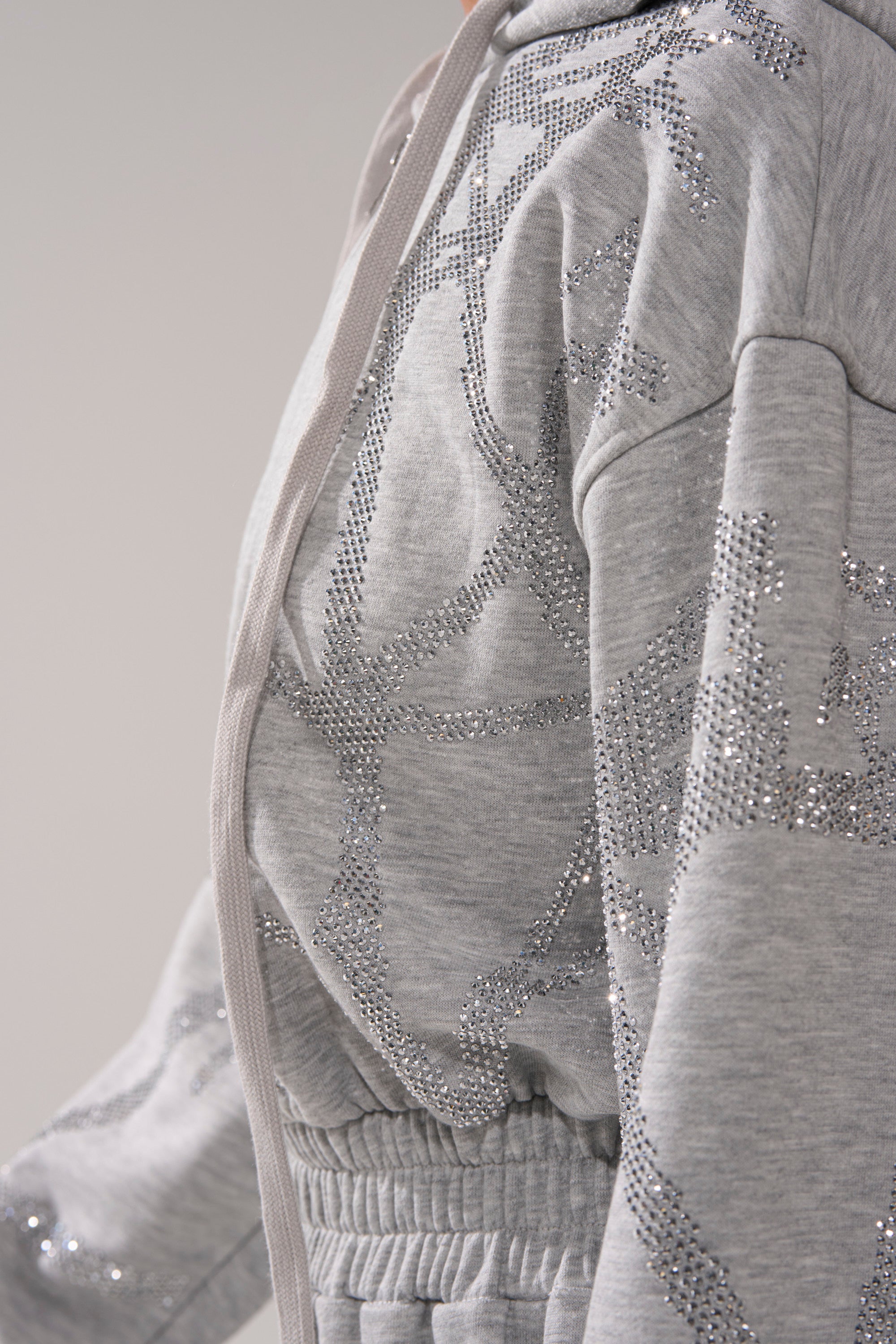 A close-up side view of a person wearing the NEVER BUGGIN PRINTED FRENCH TERRY JUMPSUIT in light gray, featuring an elastic waist and printed abstract patterns across the fabric.