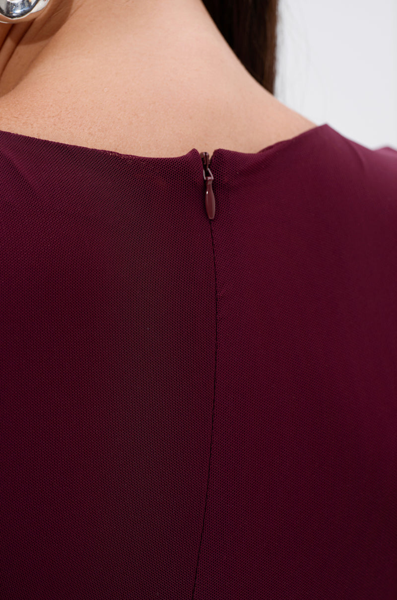 Close-up of the back of a person's neck and shoulders wearing the KEEPIN IT SIMPLE MESH JUMPSUIT IN BURGUNDY, featuring textured fabric and a small, centered closed zipper at the top. 5