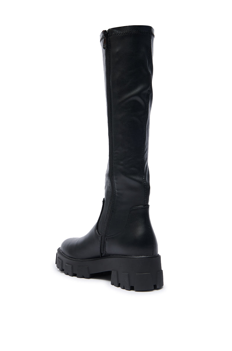 The AZALEA WANG JAYE KNEE HIGH BOOT IN BLACK features a chunky, rugged sole and side zipper, presented from a rear side angle on a white background.
