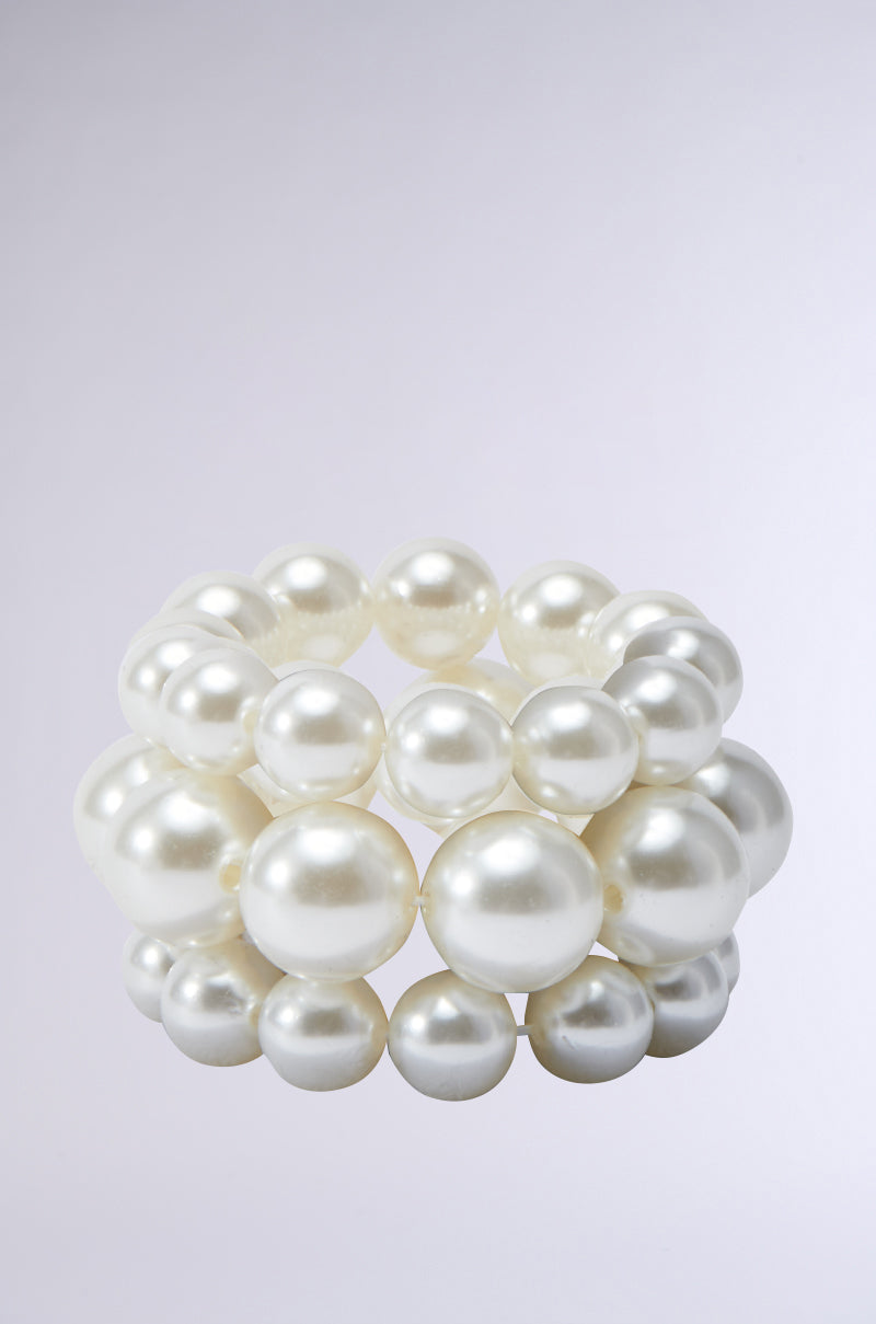 The PEARL PLEASE STRETCH BRACELET SET features a trio of bracelets adorned with large, glossy white pearls beautifully contrasted against a simple light gray backdrop. The stretchable design artfully arranges the pearls in layers, offering a luxurious and elegant look with a refined finish. 0