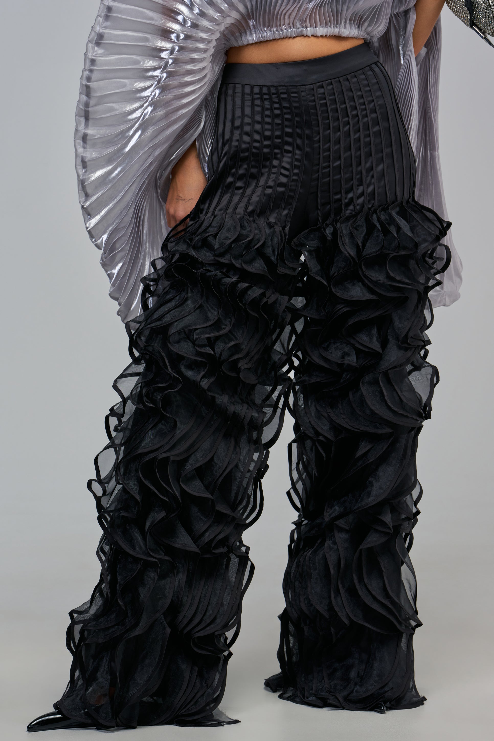 CRAZY FOR YOU PANT: high-waisted black satin ruffle pants featuring vertical pleats and layered trim from the knees down in a wide-leg silhouette.