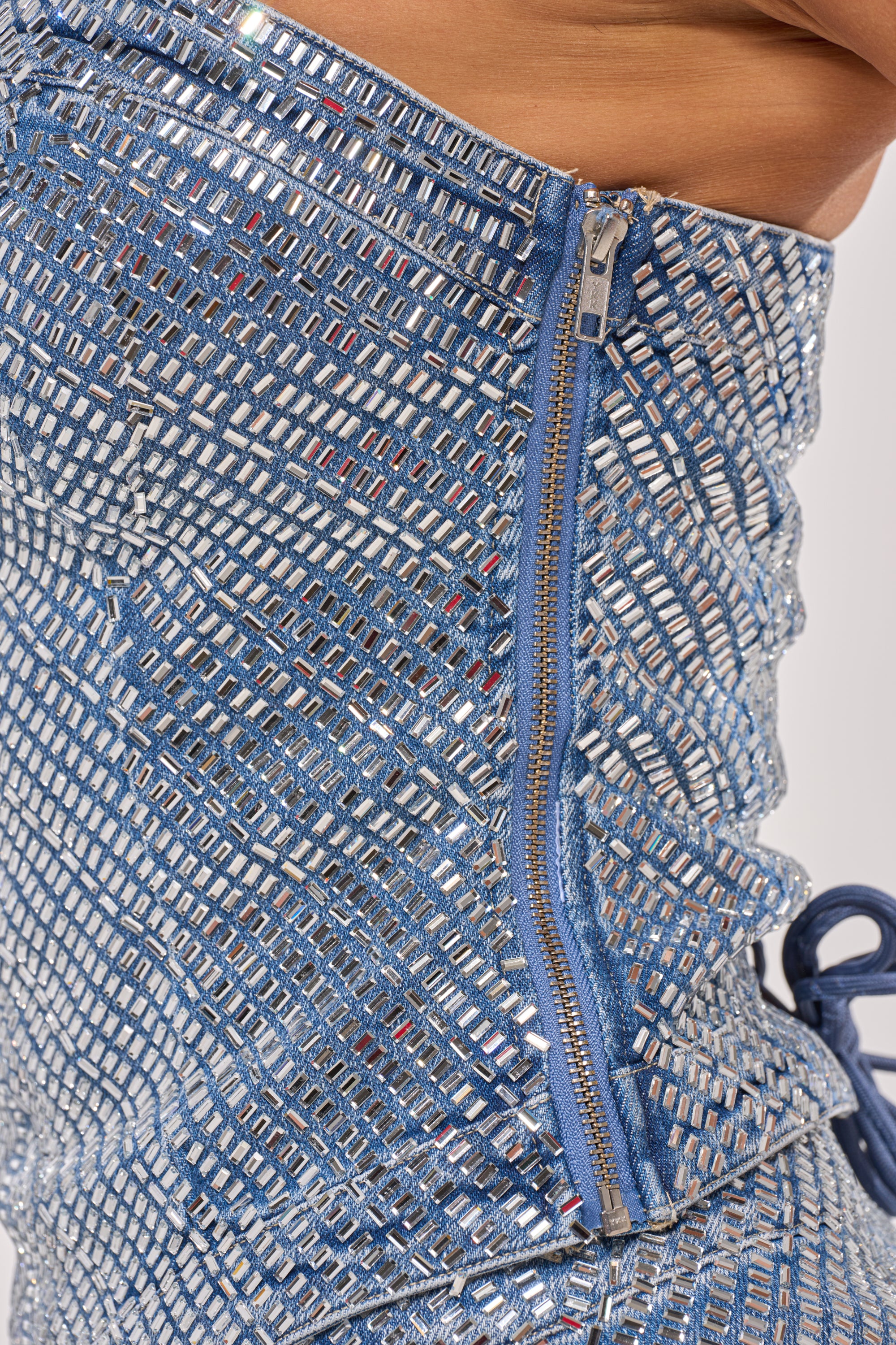 Close-up of the BLING BLING CORSET: a fitted festival piece in blue and silver sequined fabric with a blue zipper and drawstring. Its geometric, mosaic pattern creates a striking, contemporary look. 12
