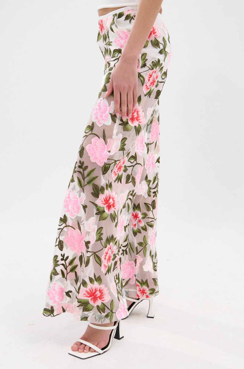 A woman models the BLOSSOM LACE PALAZZO PANTS with pink floral lace embroidery and green leaves, a wide-leg cut, and white high-heeled sandals against a plain white background.