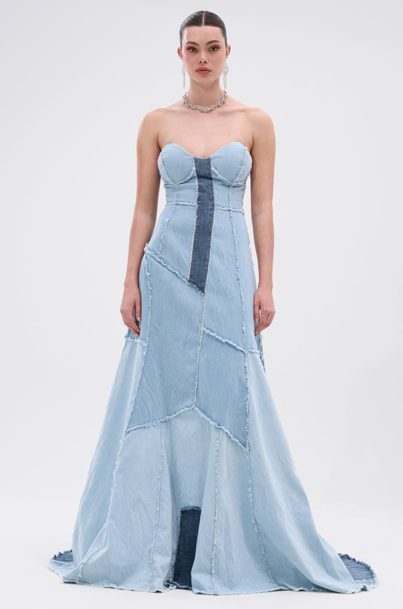 A woman models the IT'S BRITNEY PATCHWORK DENIM MAXI DRESS, a strapless mermaid silhouette maxi with patchwork denim in blue shades and frayed seams, set against a plain white background.