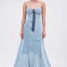 A woman models the IT'S BRITNEY PATCHWORK DENIM MAXI DRESS, a strapless mermaid silhouette maxi with patchwork denim in blue shades and frayed seams, set against a plain white background.