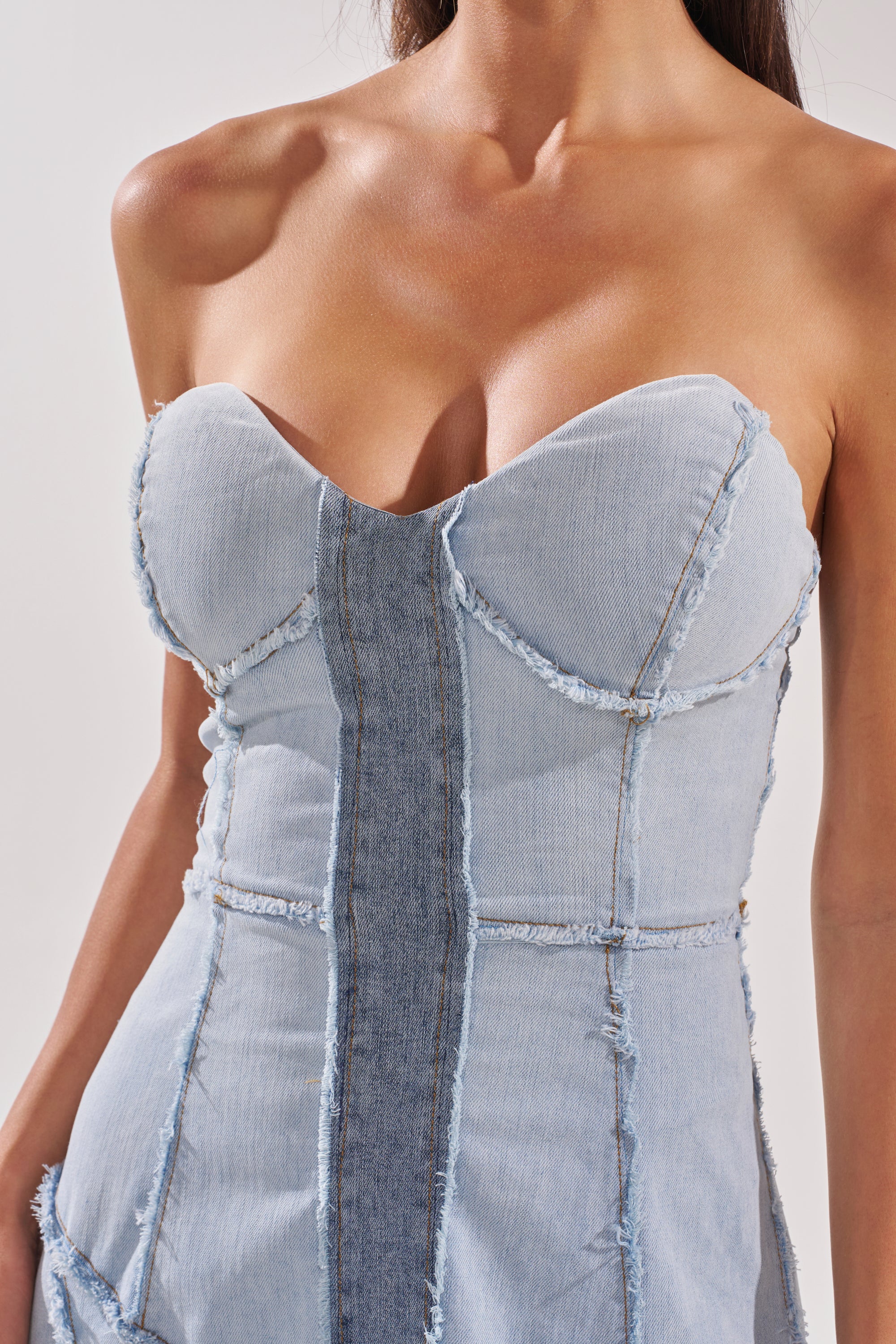 A woman wearing the IT'S BRITNEY PATCHWORK DENIM MAXI DRESS, a strapless, form-fitting denim dress with exposed seams, frayed edges, a sweetheart neckline, contrasting panels, and a mermaid skirt silhouette. 7