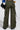 Dressed in IT IS BACK CARGO PANTS featuring an adjustable drawstring hem and high-rise waist, olive green cargo pants pair effortlessly with a multicolored top. A black bag is slung over the shoulder and dark shoes complete the ensemble, all captured from behind.