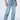 A person is modeling the EVERYTIME RHINESTONE EMBELLISHED STRAIGHT LEG JEANS in a high rise light blue wash, adorned with numerous small studs. They are also wearing a black leather vest and black leather shoes with studded details. The image is cropped at the waist and feet, focusing on the jeans.