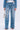 Wearing KEY TO THE CITY RELAXED FIT JEANS—inspired blue, mid-rise denim with metal key details—a person holds a small metallic chain purse and wears open-toed heels, all set against a plain white background.
