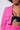 A person is seen wearing the vibrant BETTER LUCK CROP BLAZER in fuschia, along with matching pants. The blazer features utility-style breast pockets, and underneath it, they sport a black, shiny crop top. The image is cropped to show only the torso and part of the face.