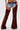 A person models INCREDIBLE VELVET DENIM CHAPS over cowboy boots, paired with distressed shorts and a wide belt, embodying modern cowgirl couture against a plain white background.