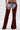 A person wears the INCREDIBLE VELVET DENIM CHAPS—distressed denim shorts with attached brown velvet chaps and a brown belt—for a bold cowgirl couture look that features exposed upper thighs.