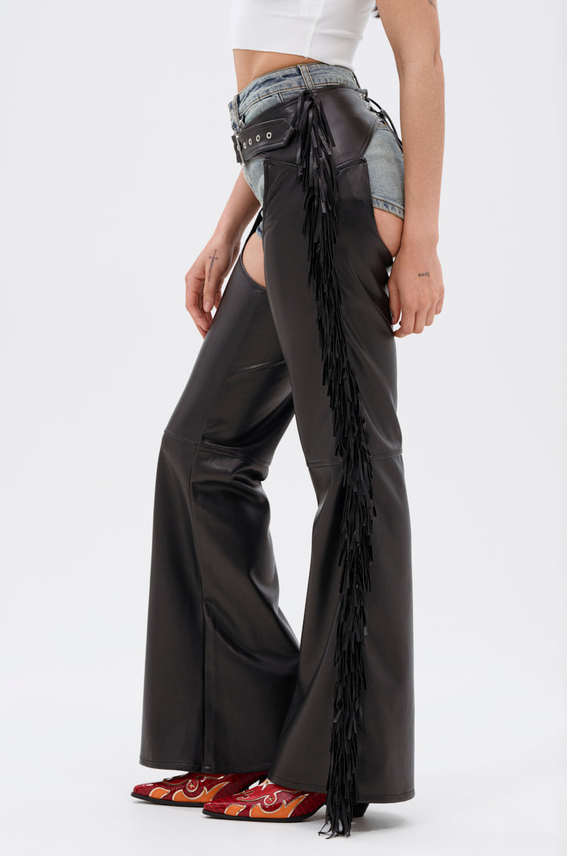 Wearing RODEO FRINGE FAUX LEATHER CHAPS over denim shorts, a white crop top, and red western boots, this look captures playful Western-chic Bottoms style against a plain white backdrop.