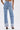 A person wearing IN THE MOOD DENIM PANT with cuffed hems and heeled sandals stands facing away, highlighting the straight-leg fit, two back pockets, and a visible brand label on the waistband.