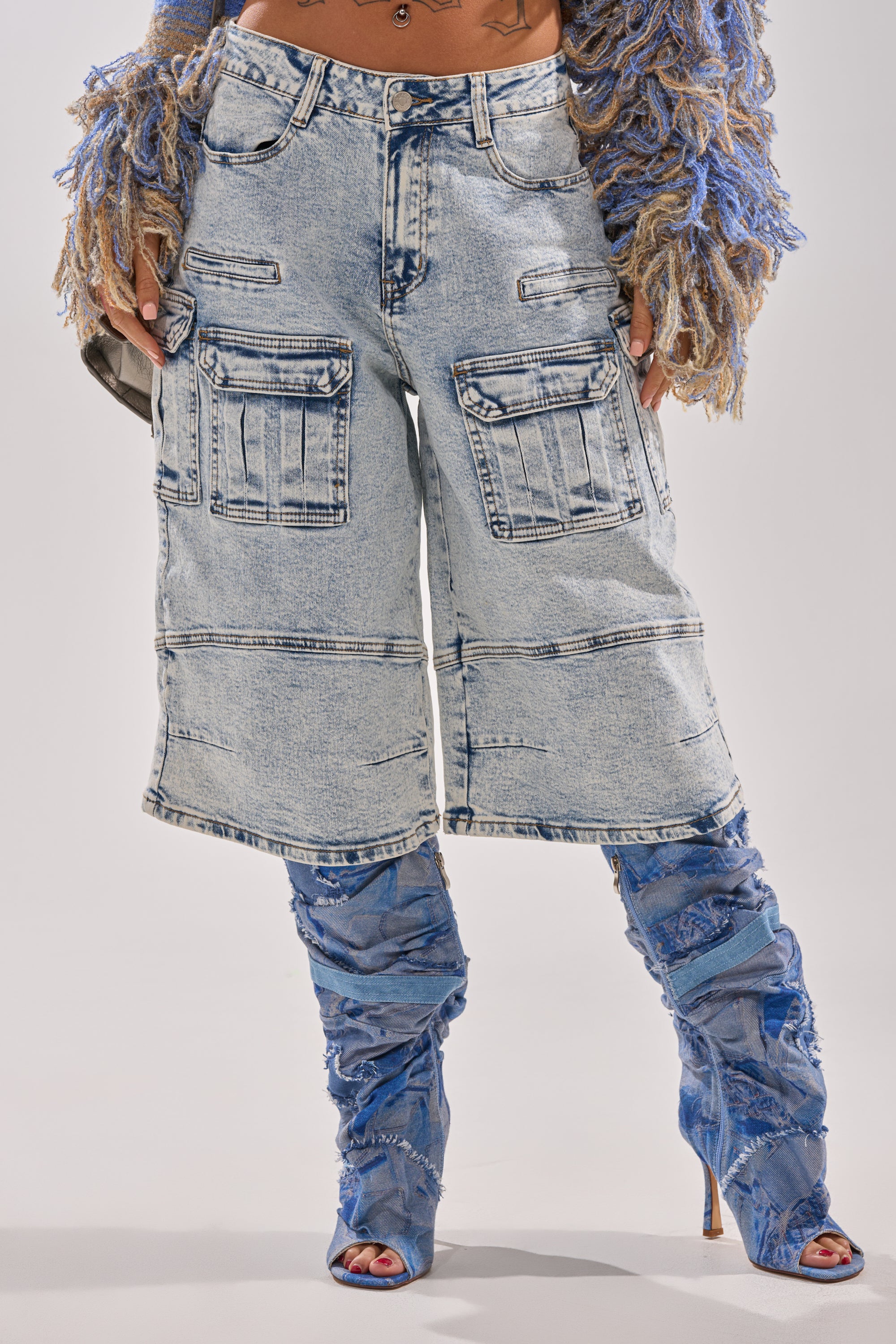 Wearing FORGET ME NOT DENIM CARGO BERMUDA SHORTS in light blue acid-wash, paired with blue textured knee-high heeled boots and a fringed sweater. The cropped image shows only the lower body. 6