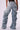 Person wearing OH YEAH BABY DENIM PANT from JCR Trading LTD in a light-washed, extremely oversized style paired with a black top. The mid-rise waist jeans are gathered at the ankles, creating a billowing, ruched baggy effect. The back pockets and belt loops are visible against the white background.