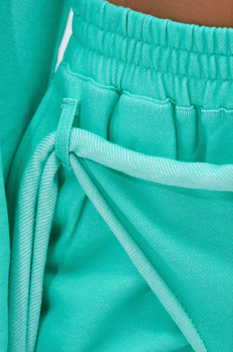 Close-up of a person wearing the ISSA JOGGER PANT IN TIFFANY, featuring a high-rise elastic waistband with a knotted drawstring. The soft fabric and relaxed fit provide ultimate comfort. 9
