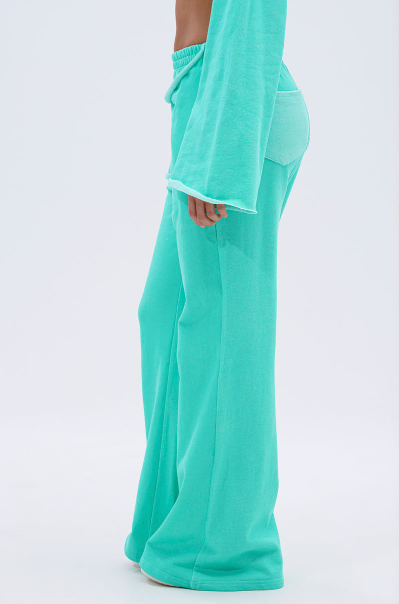 Person wearing the ISSA JOGGER PANT IN TIFFANY, a loose-fitting, bright turquoise wide-leg jogger, shown from the lower torso down against a plain light background. 4