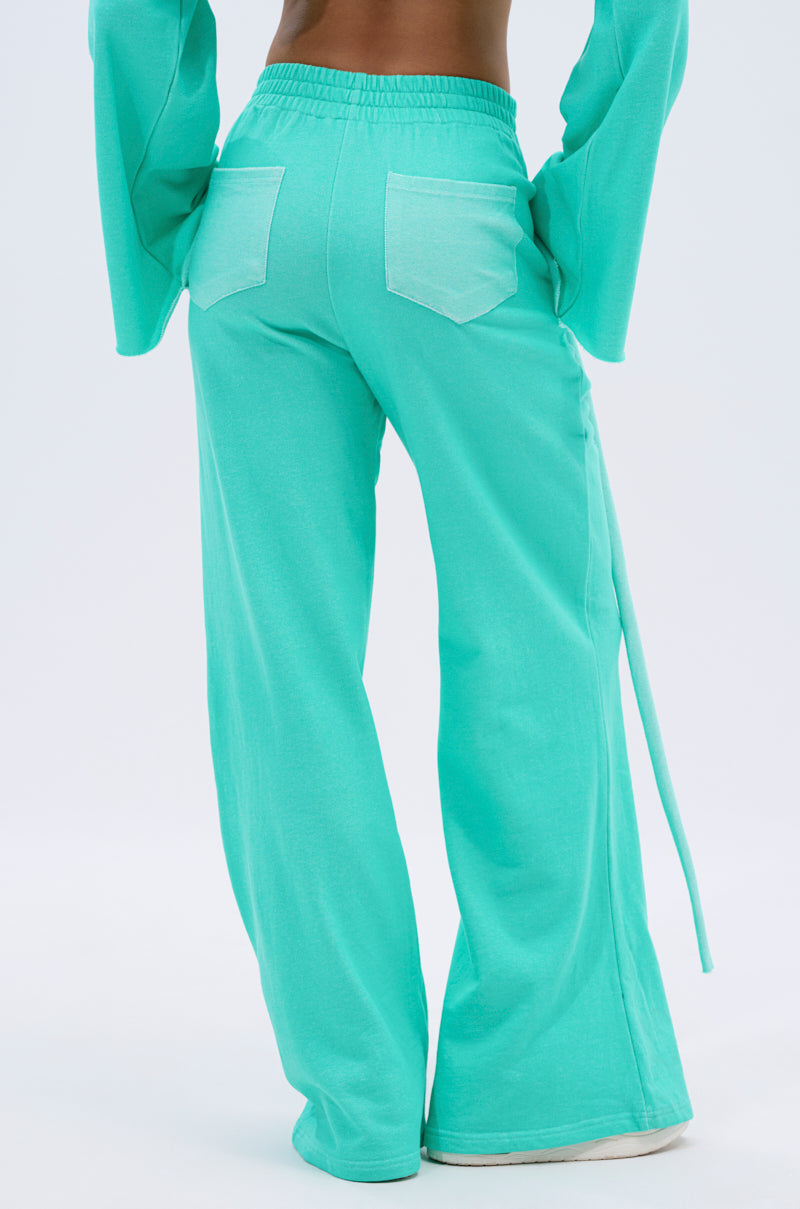 Person wearing loose-fitting, Tiffany-colored ISSA JOGGER PANT and a matching wide-sleeve top, shown from the back. The wide-leg joggers have two large square back pockets and a long side fabric tie. 5