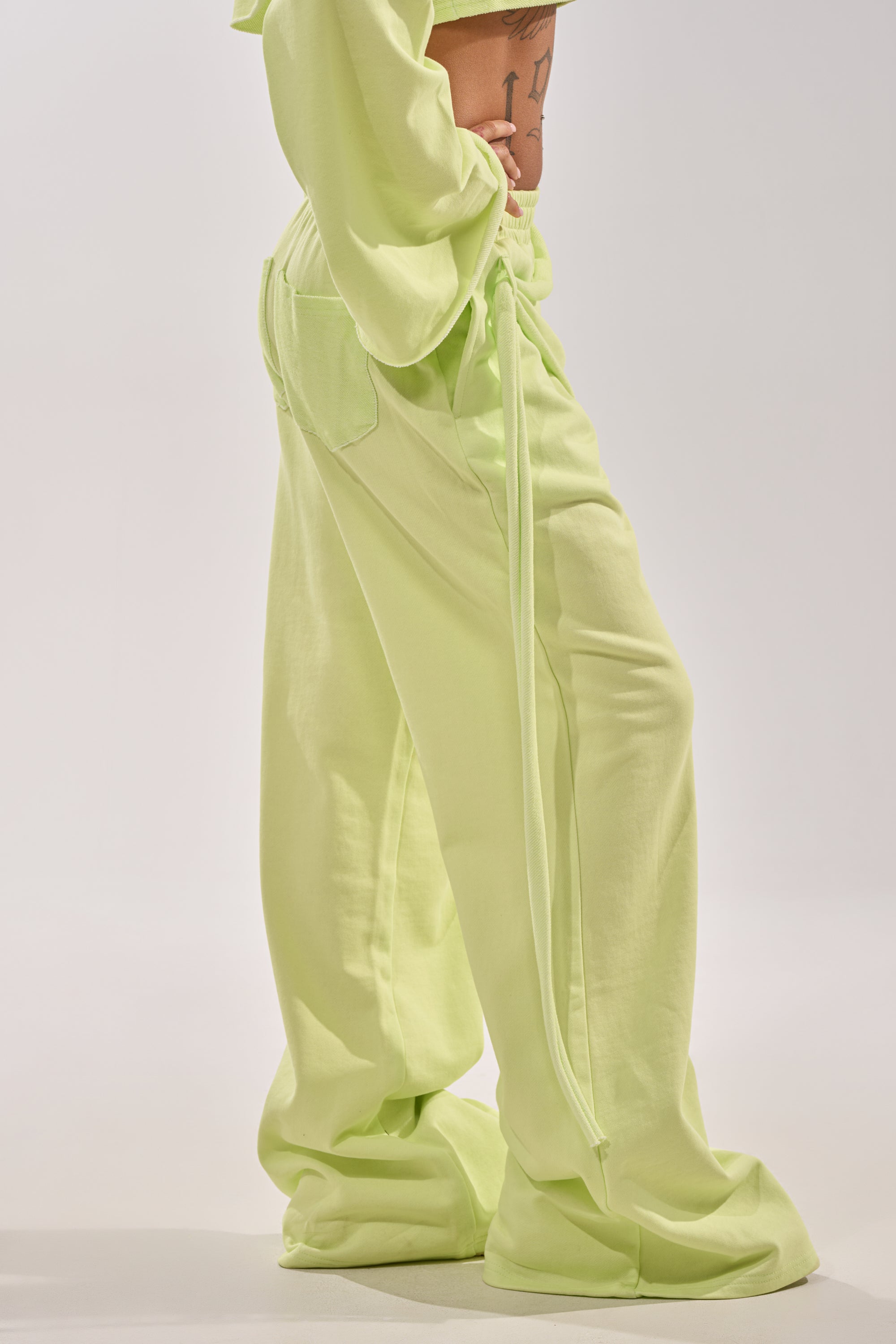 A person models the TRY ME BABY WIDE LEG JOGGER in lime, featuring a drawstring waist. Only the lower torso and legs are shown against a plain, light background. 3