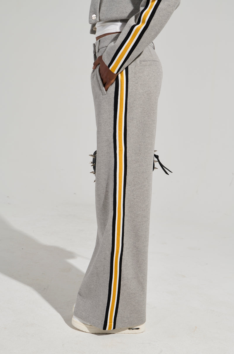 A person is wearing the STAY WITH ME WIDE LEG PANT in gray, featuring color block yellow and black stripes running down the sides. They are also sporting a matching top with a stripe on the sleeve and white sneakers, against a plain light gray background.