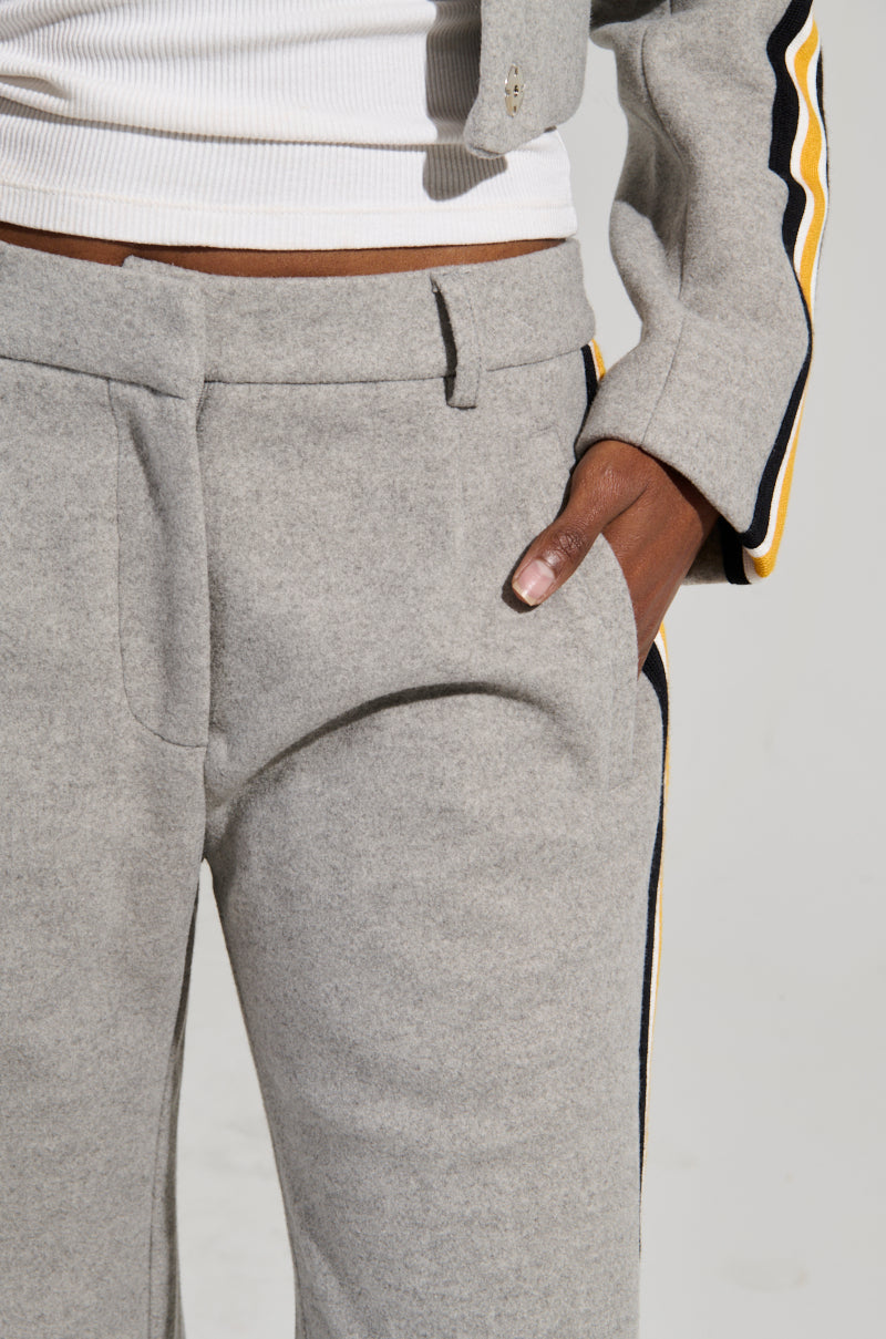 A person wearing light gray STAY WITH ME WIDE LEG PANT and a matching top featuring dark and yellow color block stripes stands with one hand in a pocket. The cropped view showcases the high-rise fit, emphasizing the texture and design of the clothing.