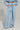 A person is dressed in Honey Honey wide-leg pants with a high-rise design, paired with a matching light blue cropped jacket. The ensemble, made from a soft cotton blend knit, has a relaxed fit and includes pockets for ultimate comfort. They pose against a plain background with hands casually tucked in.