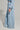 A person stands sideways wearing the HONEY HONEY WIDE LEG PANTS in a light blue, loose-fitting ensemble that includes a cropped top and high-waisted pants with a drawstring waist. The cotton blend knit texture of the outfit contrasts perfectly against the plain, light gray background.