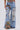 Wearing the THOUGHT I KNEW YOU RELAXED DENIM WITH BROCADE—high-waisted, wide-leg jeans with large rips revealing floral jacquard panels and frayed hems—paired with a floral top for a bold, standout look.