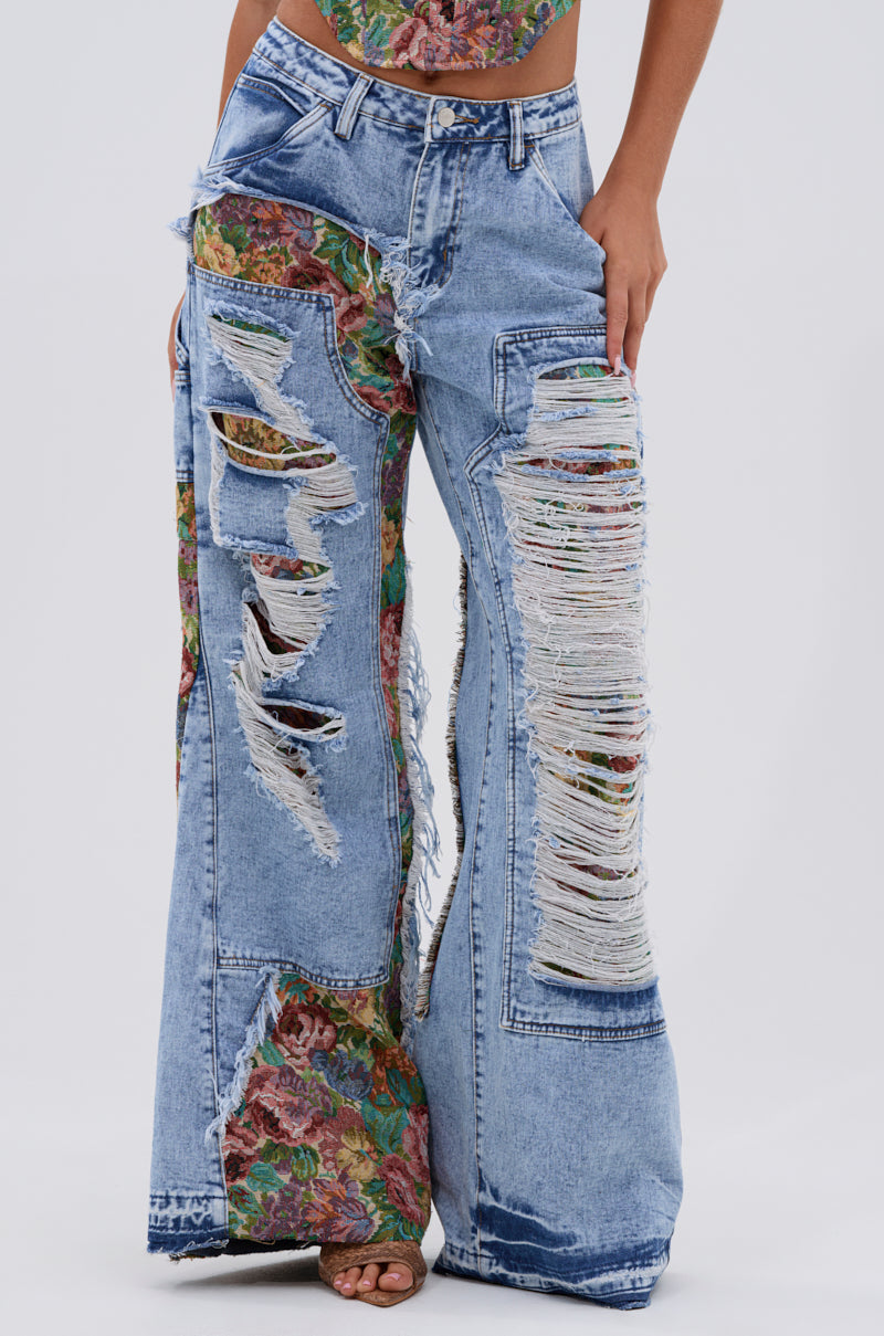 Wearing THOUGHT I KNEW YOU RELAXED DENIM WITH BROCADE: high-waisted, wide-leg jeans with heavy distressing, large rips revealing colorful floral jacquard patches, frayed edges, and an artistic style.