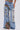 Wearing THOUGHT I KNEW YOU RELAXED DENIM WITH BROCADE: high-waisted, wide-leg jeans with heavy distressing, large rips revealing colorful floral jacquard patches, frayed edges, and an artistic style.