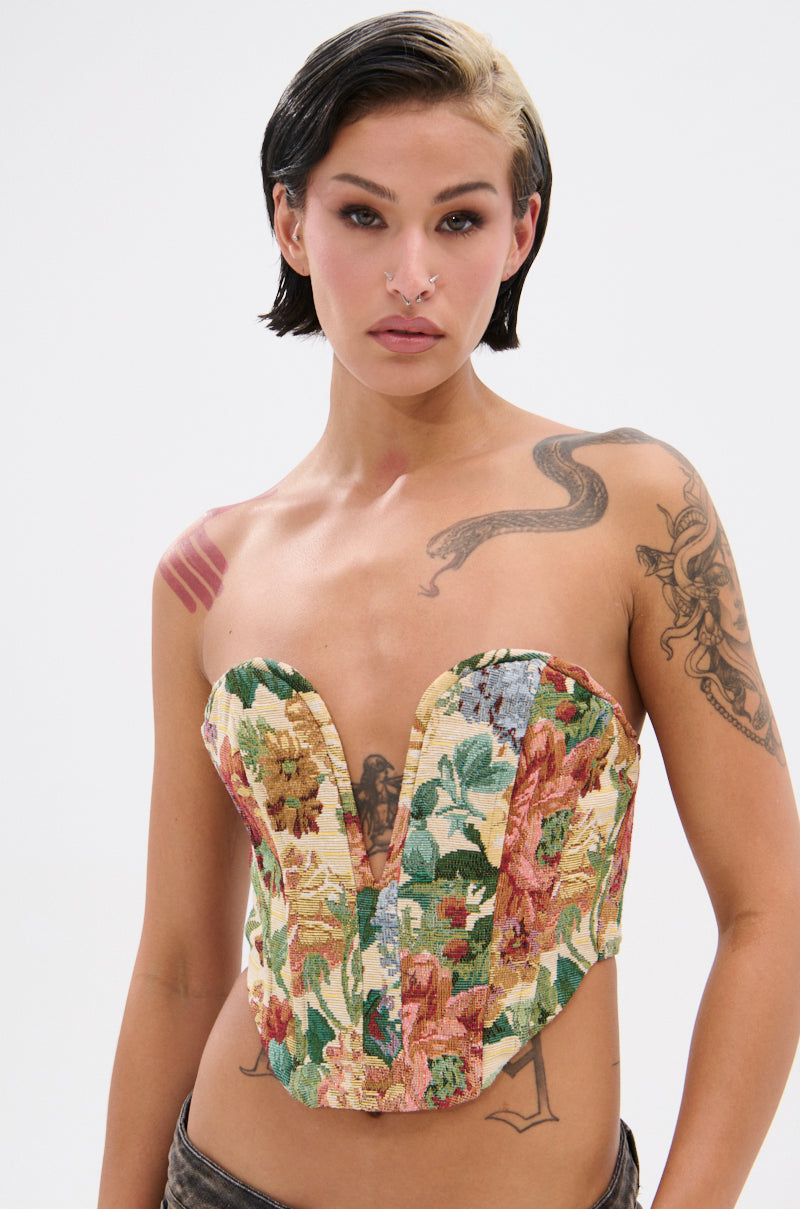 A person with short dark hair and a light streak poses in the BRIGETTE DISTRESSED JACQUARD CORSET, featuring a sweetheart neckline. They have visible tattoos, facial piercings, and a neutral expression against a plain background.